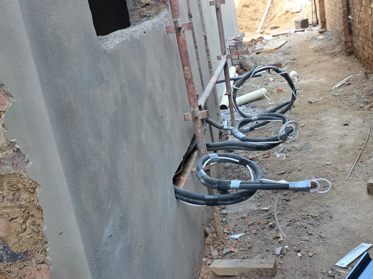 Armoured cables run along a wall on a construction site ahead of the DB installation