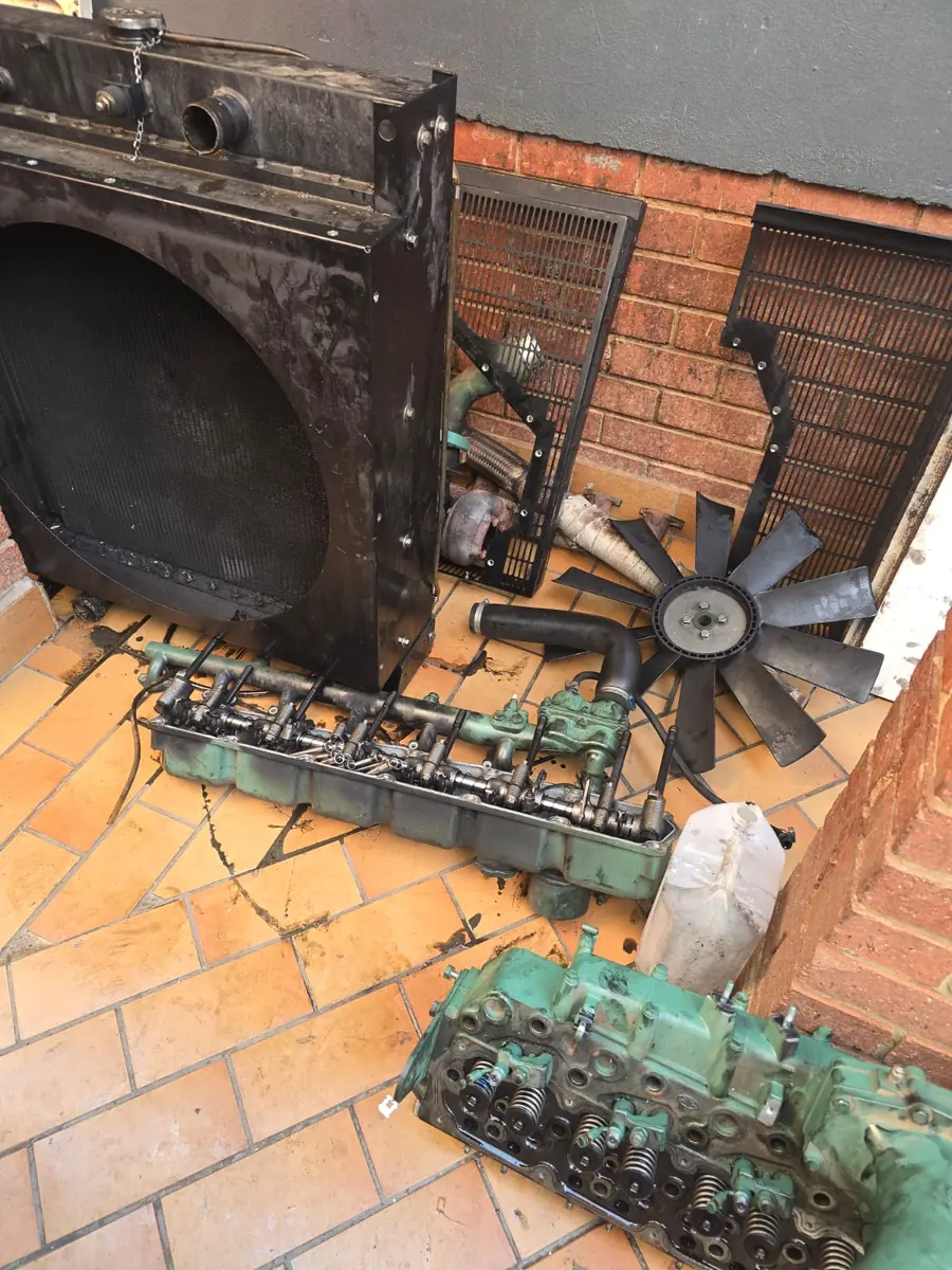 Generator radiator, cooling fan and cylinder head removed and laid out during an engine overhaul