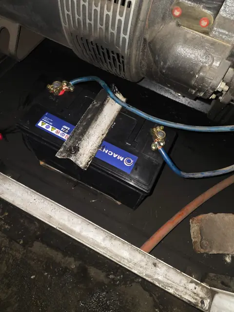Starter battery fitted beneath the alternator on a standby diesel generator during a repair call-out