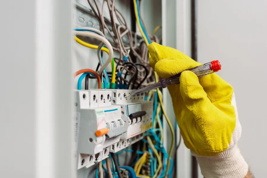 Electromech Electrical Services electrician inspecting wiring with a screwdriver